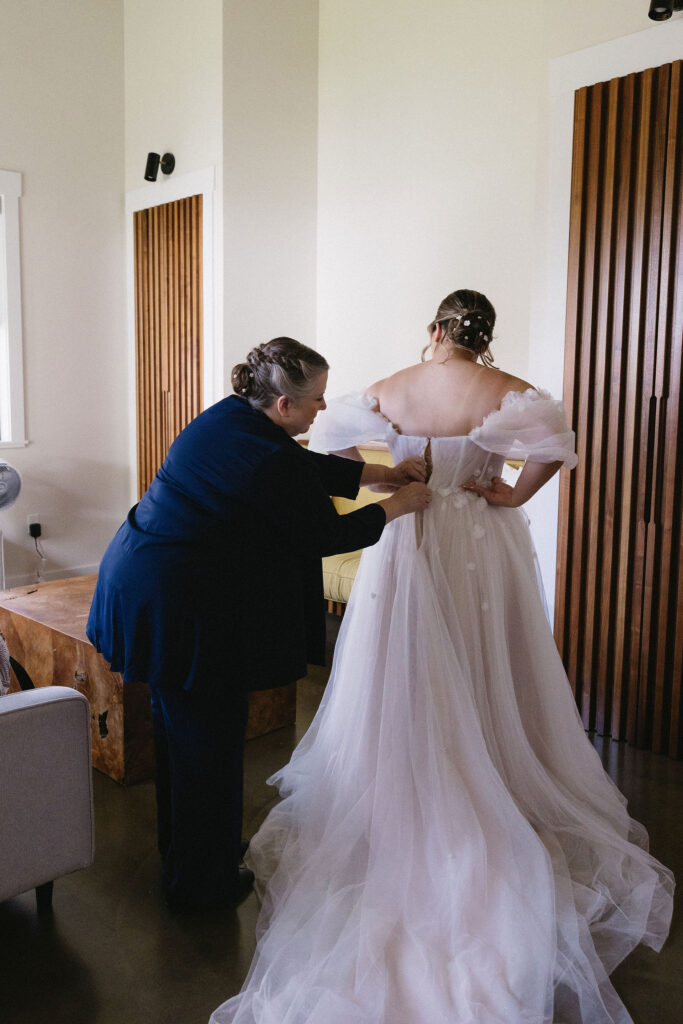 mother of the bride helping her with her wedding dress