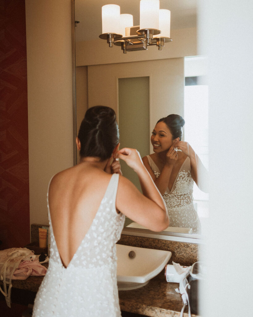 bride putting on her jewelry before the ceremony